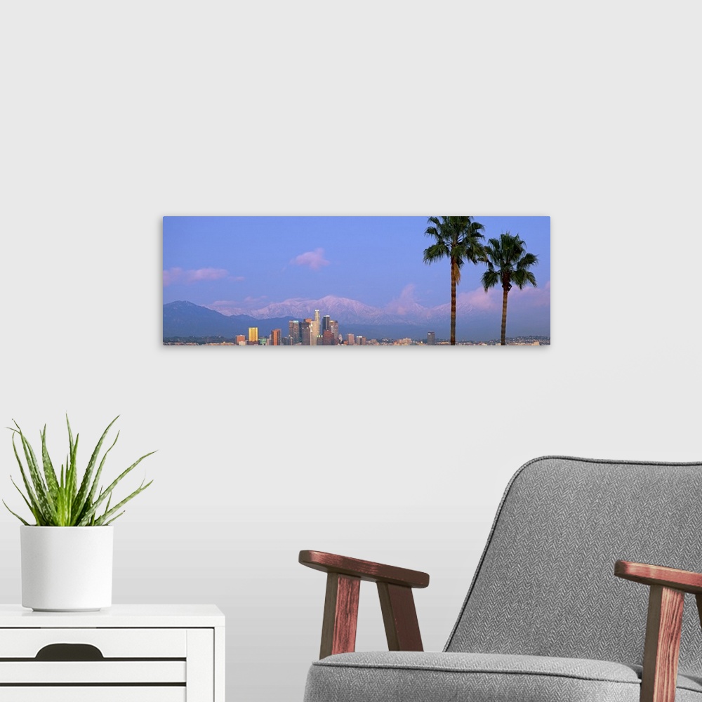 A modern room featuring Panoramic photograph of skyline and palm trees under a cloudy sky with mountain silhouettes in th...