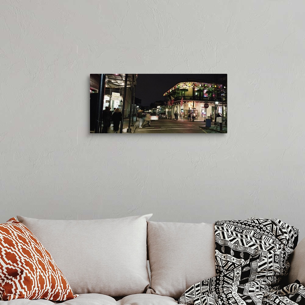 A bohemian room featuring Picture taken of a street in New Orleans with buildings lit up and people walking along the sides.