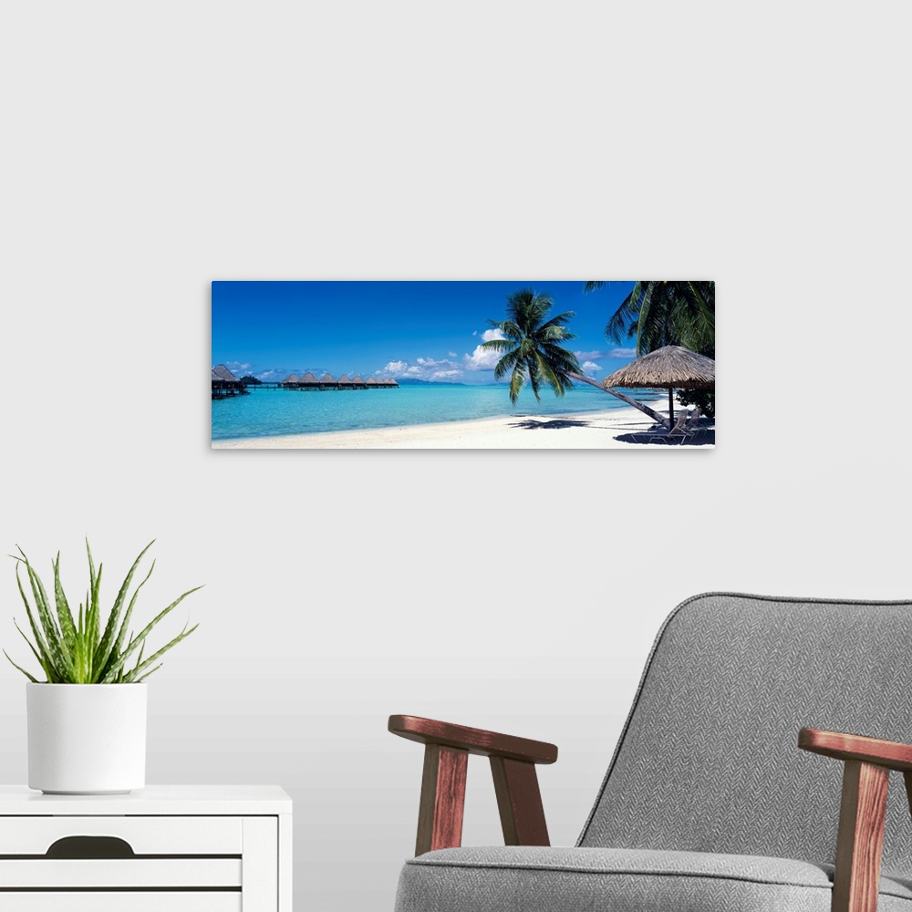 A modern room featuring This wall art is a restful beach retreat with clear water and skies captured in a panoramic photo...