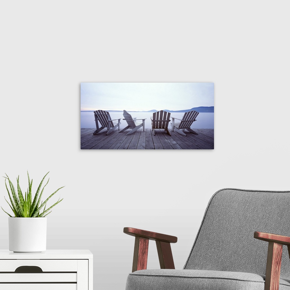 A modern room featuring Adirondack chair art of four chairs at the edge of a dock on a misty lake in summer.