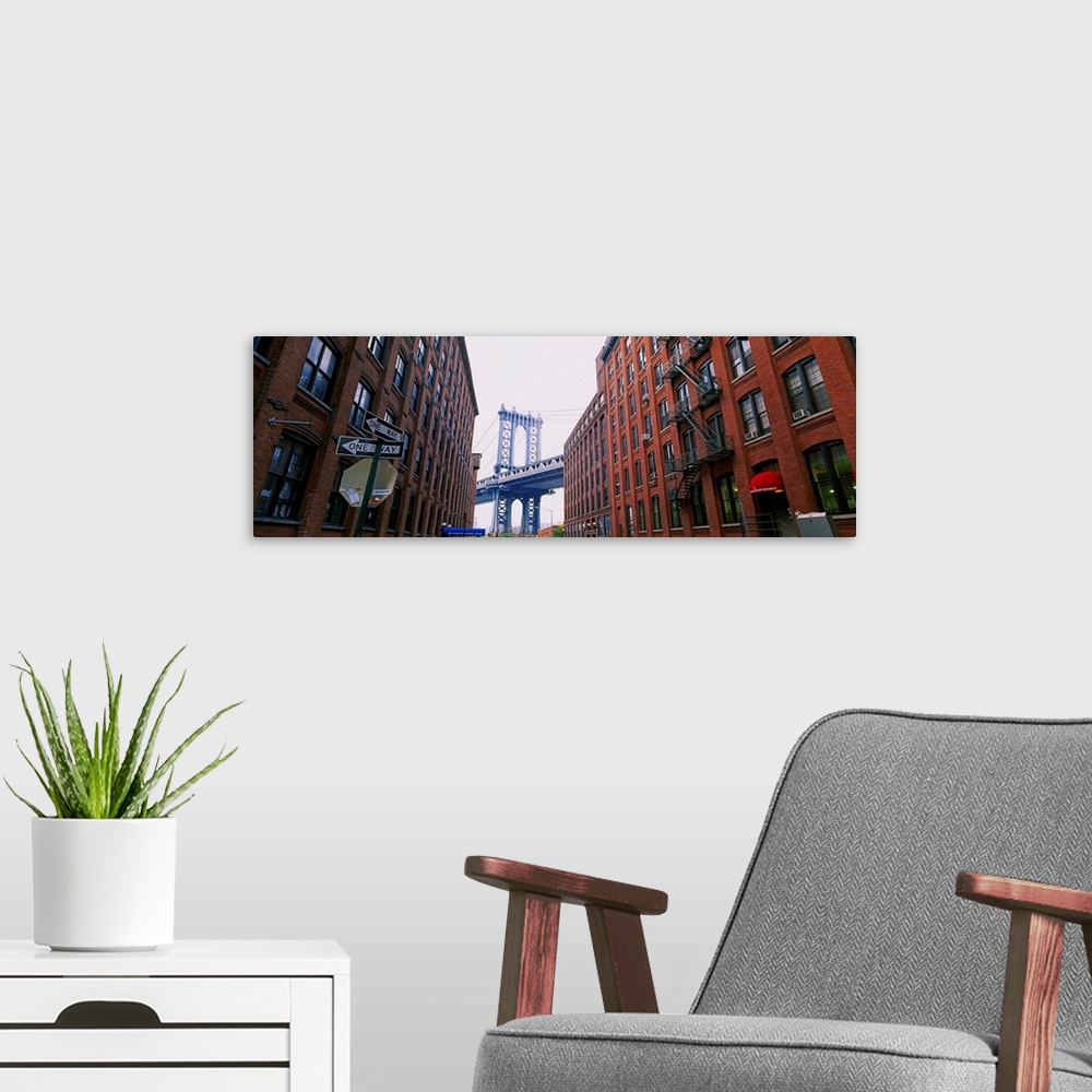 A modern room featuring Low angle view of a suspension bridge viewed through buildings, Manhattan Bridge, Brooklyn, New Y...