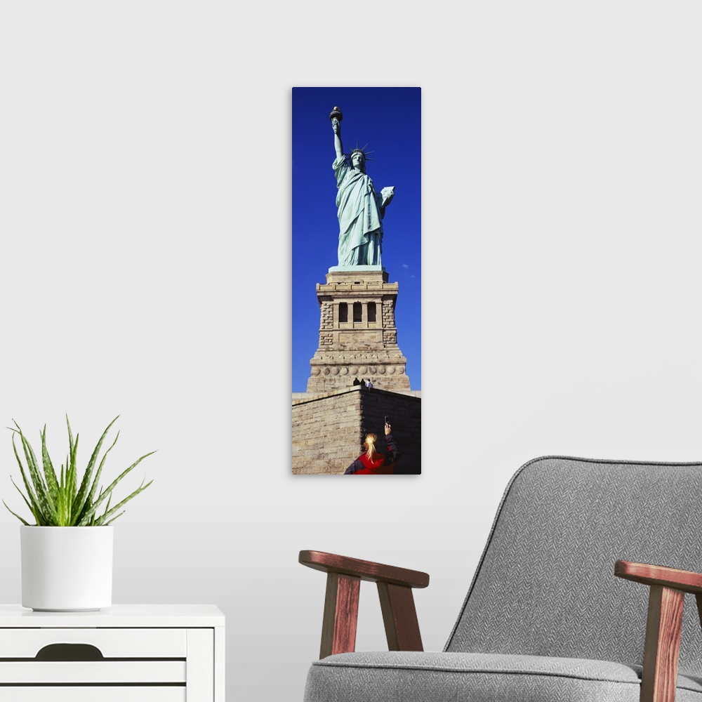 A modern room featuring Low angle view of a tourist taking a picture of a statue, Statue of Liberty, Liberty State Park, ...