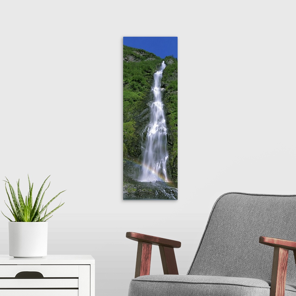 A modern room featuring Vertical panoramic photograph of water cascading over rocks with small rainbow at the bottom.