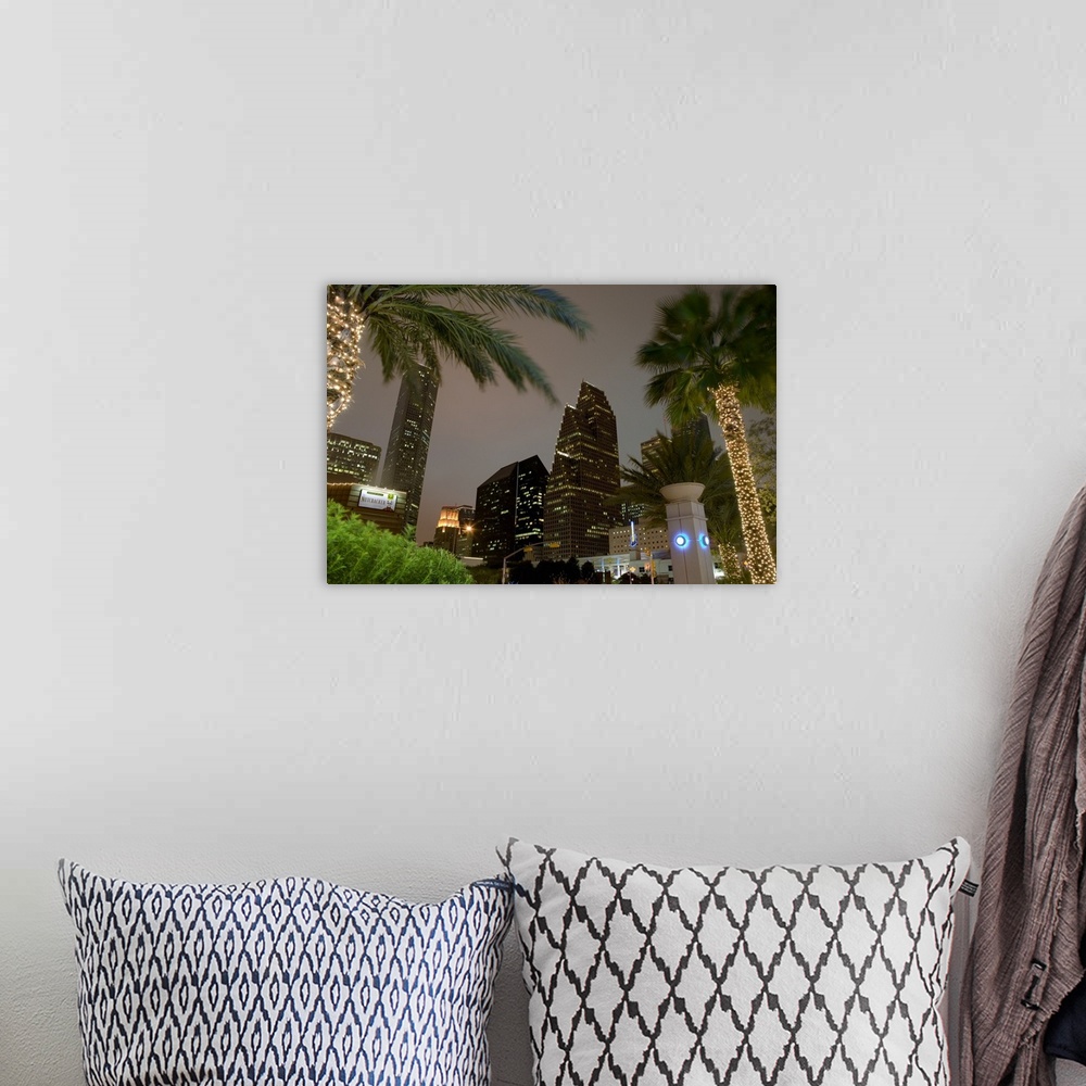 A bohemian room featuring Landscape, large photograph, looking up through several palm trees at the lit skyscrapers of the ...
