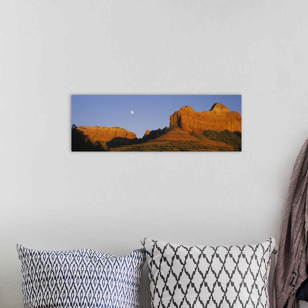 A bohemian room featuring A panoramic photograph of the setting sun illuminating rock cliffs as the moon rises between them.