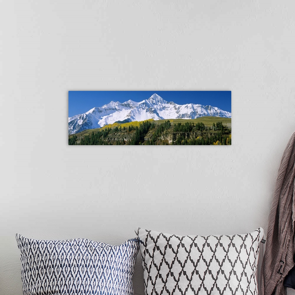 A bohemian room featuring Big, landscape, panoramic photograph of the snow covered Rocky Mountains beneath a blue sky.  Tak...