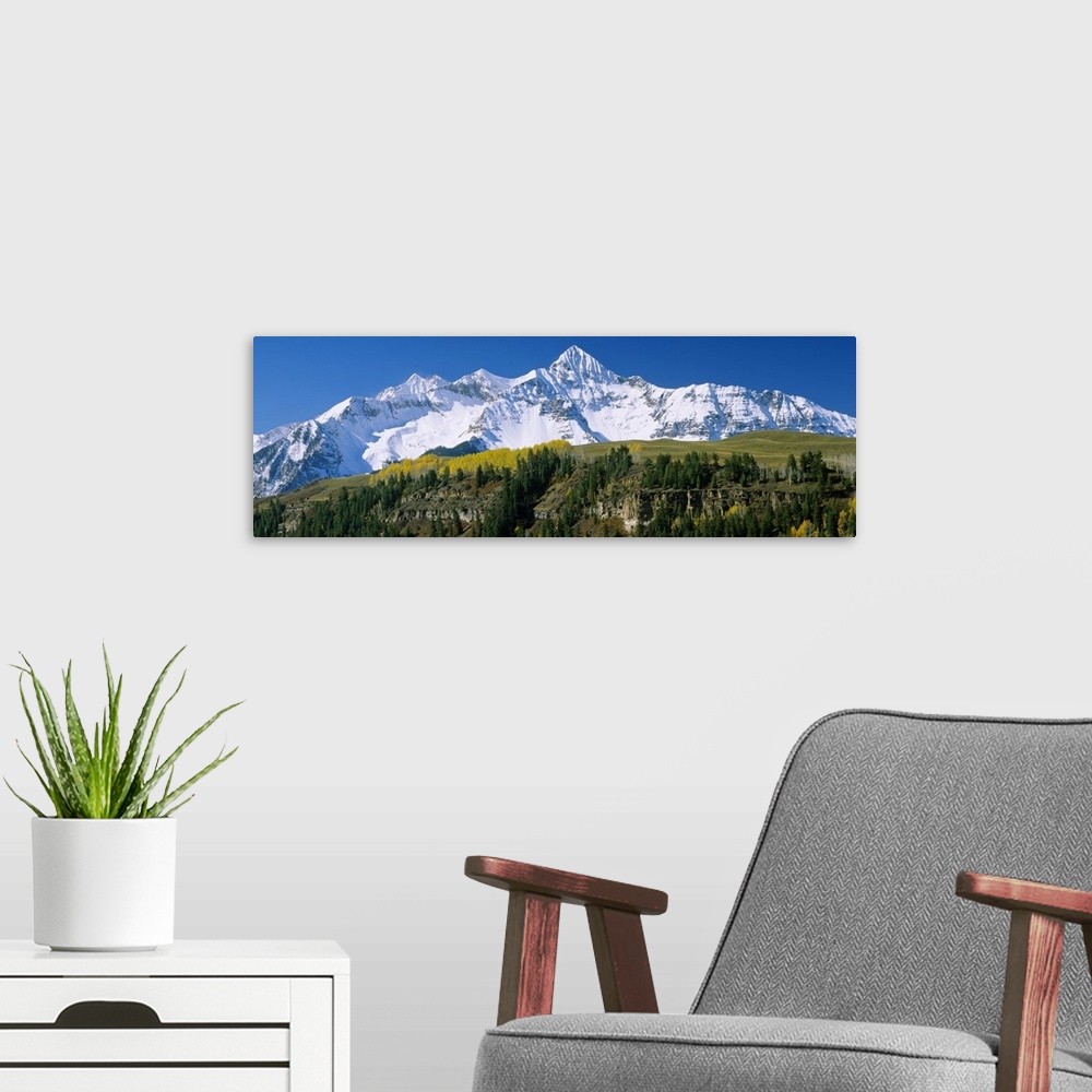 A modern room featuring Big, landscape, panoramic photograph of the snow covered Rocky Mountains beneath a blue sky.  Tak...