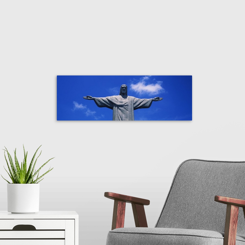 A modern room featuring Panoramic, low angle photograph of the Christ the Redeemer statue, from the waist up, against a b...