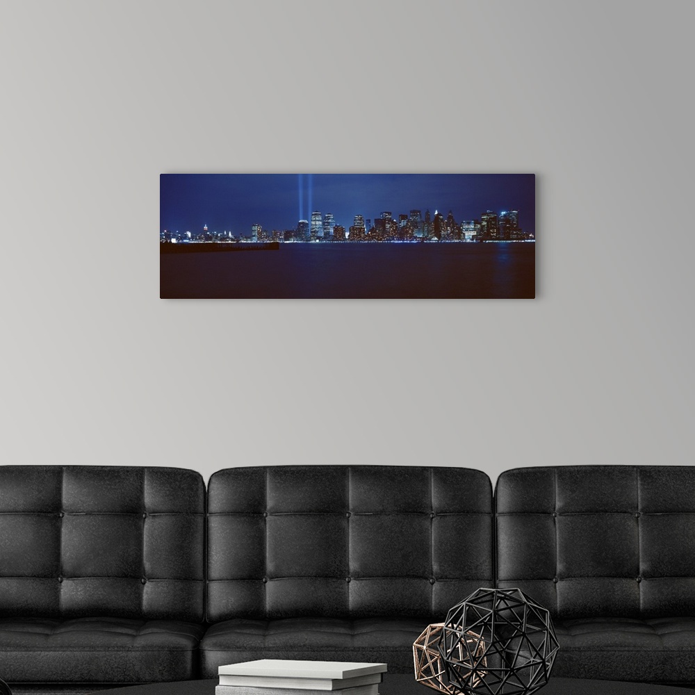 A modern room featuring Panoramic photograph of lit up skyline and waterfront at night.