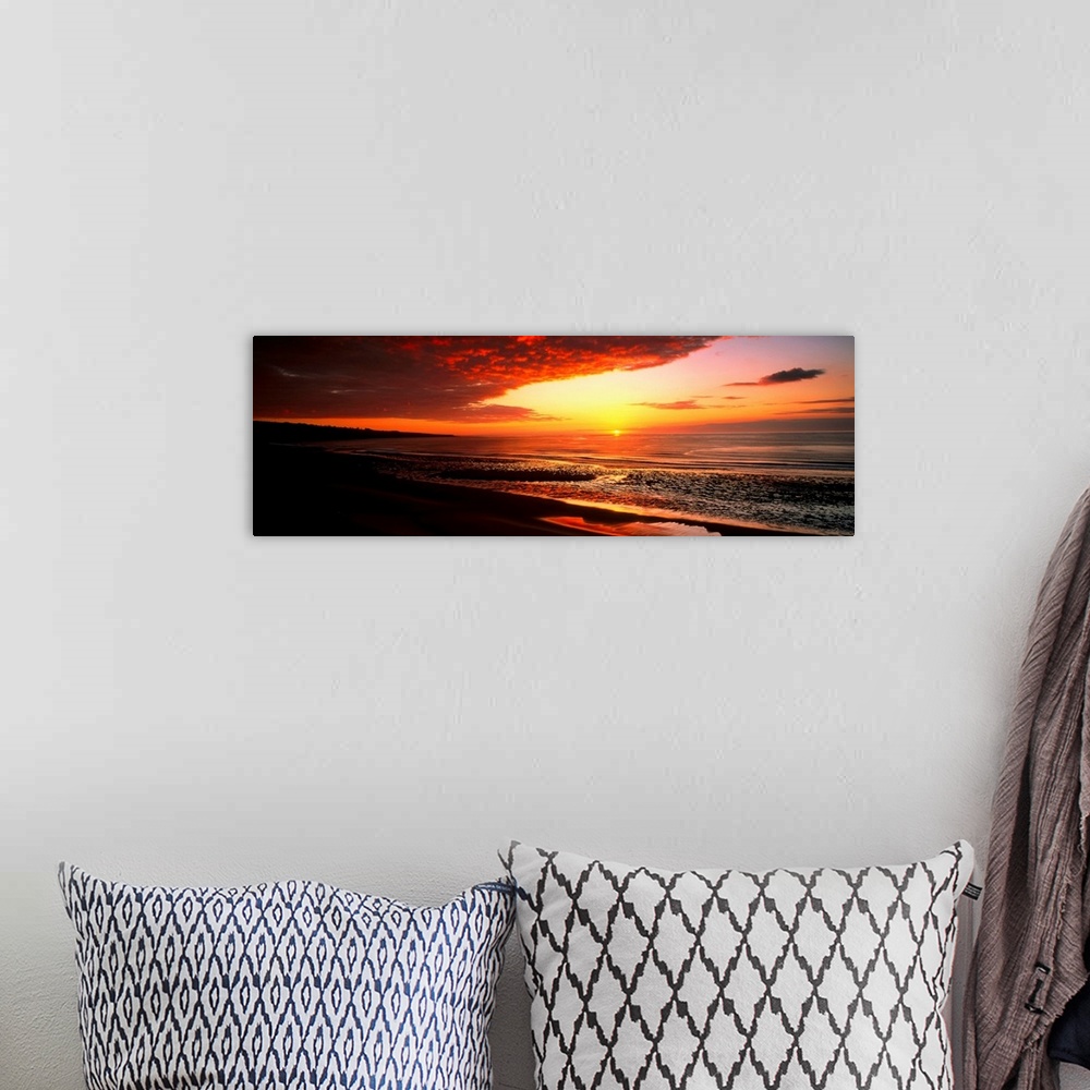 A bohemian room featuring This is a panoramic photograph a flat sandy beach and sunset.