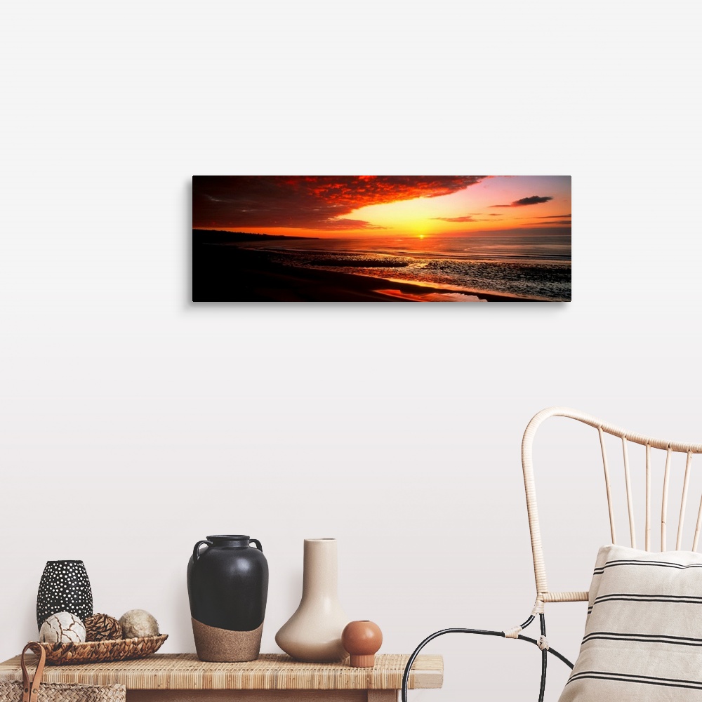 A farmhouse room featuring This is a panoramic photograph a flat sandy beach and sunset.