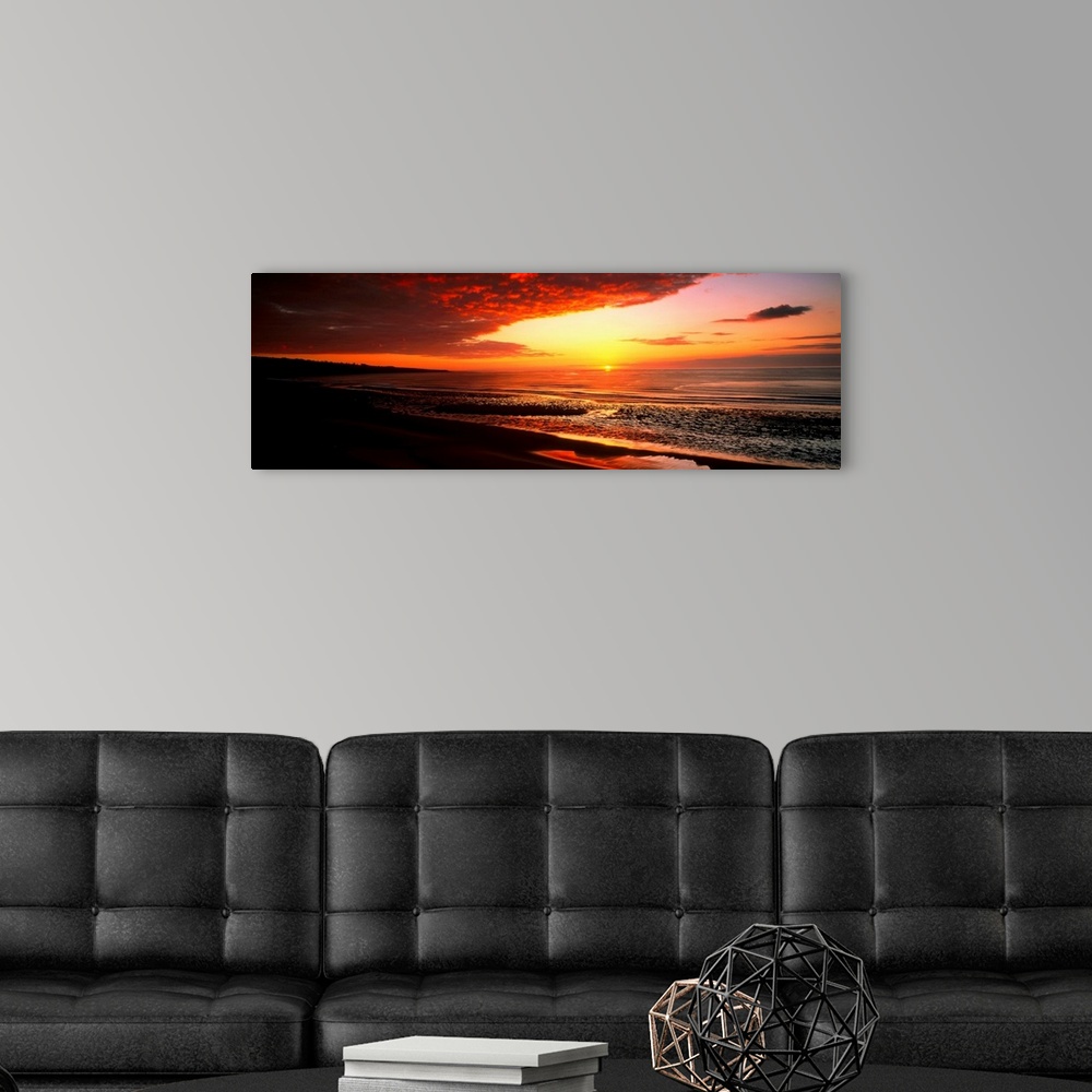 A modern room featuring This is a panoramic photograph a flat sandy beach and sunset.