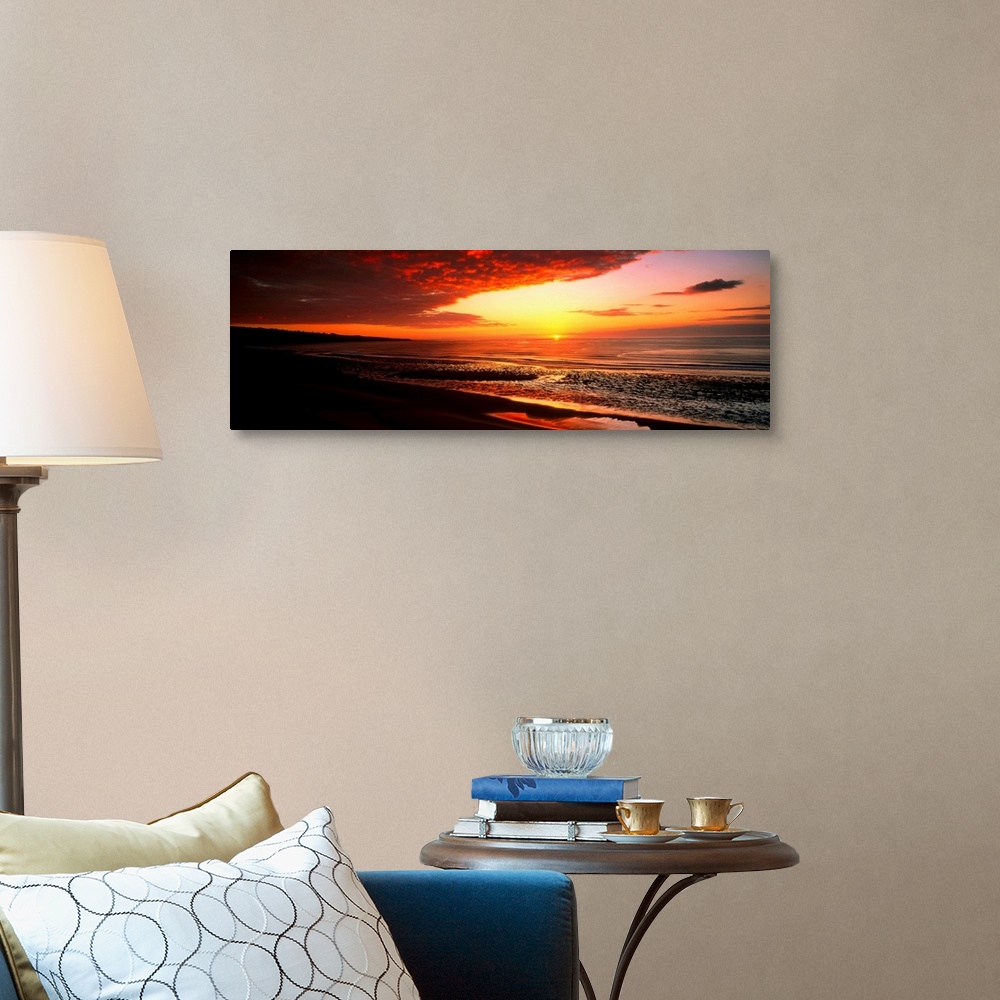 A traditional room featuring This is a panoramic photograph a flat sandy beach and sunset.