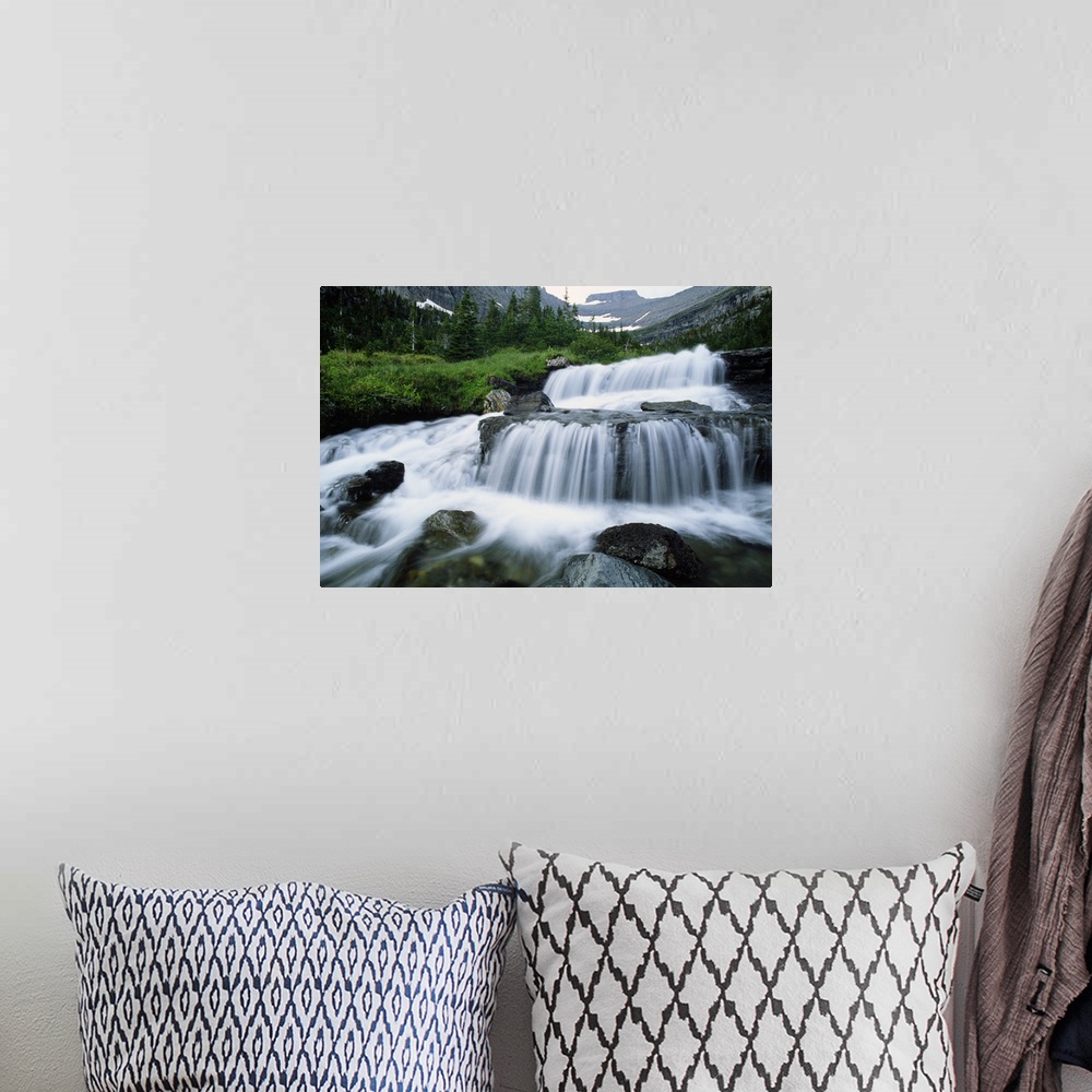 A bohemian room featuring Big print of water rushing down small waterfall areas of rocks in a river surrounded by rugged mo...