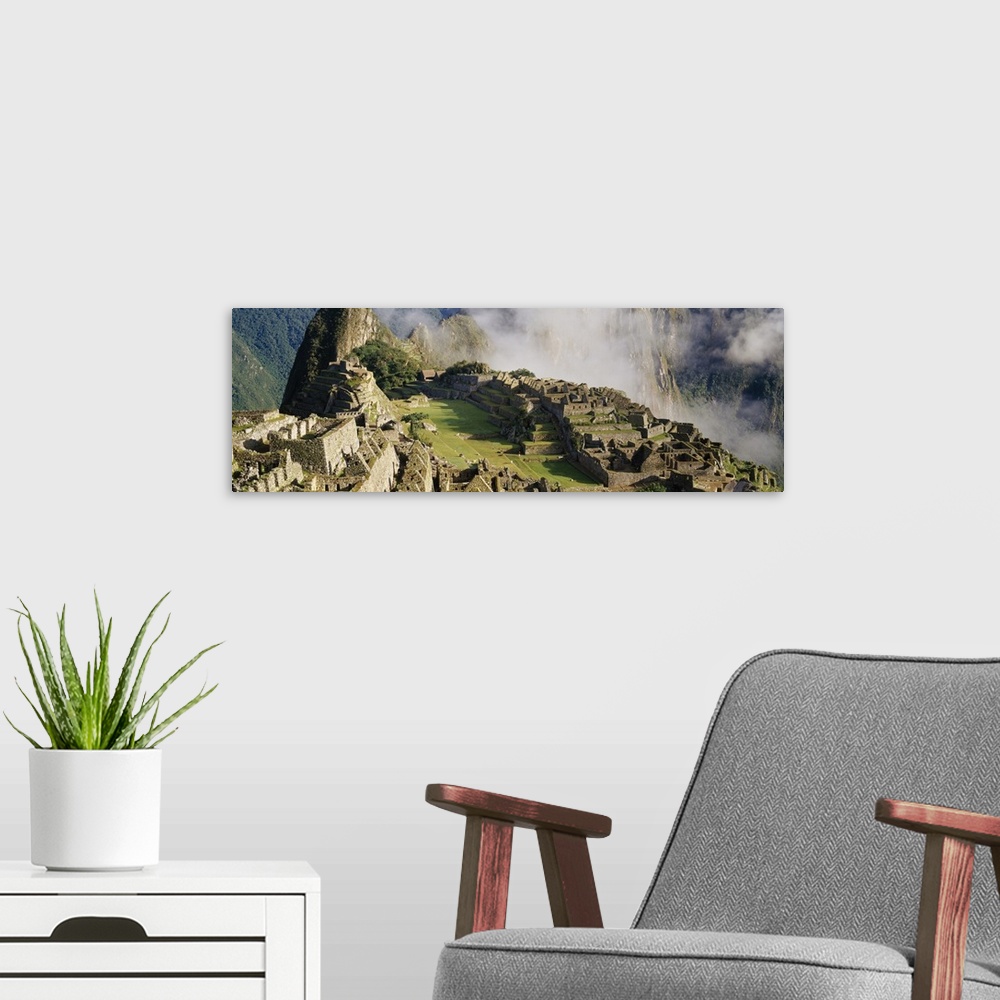 A modern room featuring Oversized landscape photograph of Machu Picchu in the sunlight, thin clouds in the background, in...
