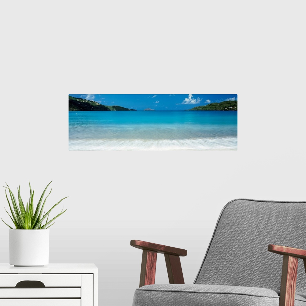 A modern room featuring Panoramic photograph of clear water in a calm sea washing up a tropical beach.