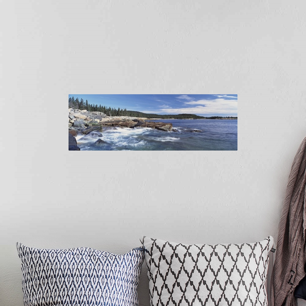 A bohemian room featuring Panoramic photograph of rocky shoreline with surf.  There are trees in the distance under a cloud...