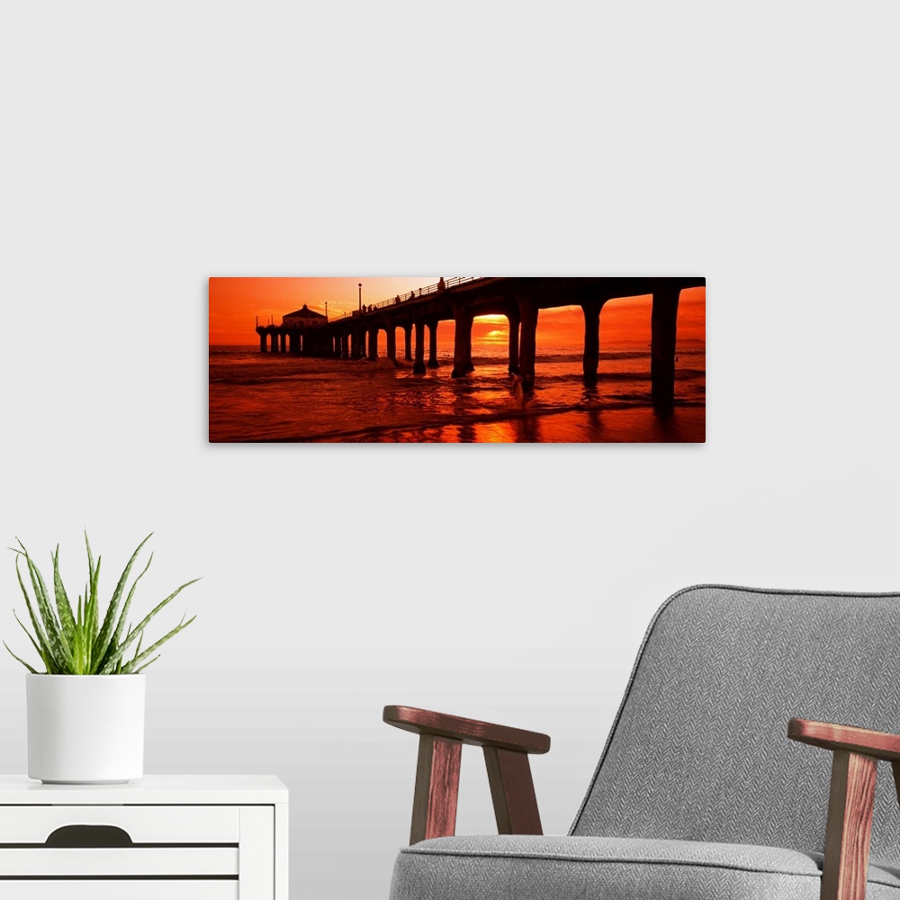 A modern room featuring Panoramic photograph on a big canvas of a silhouetted Manhattan Beach Pier at an angle, in front ...