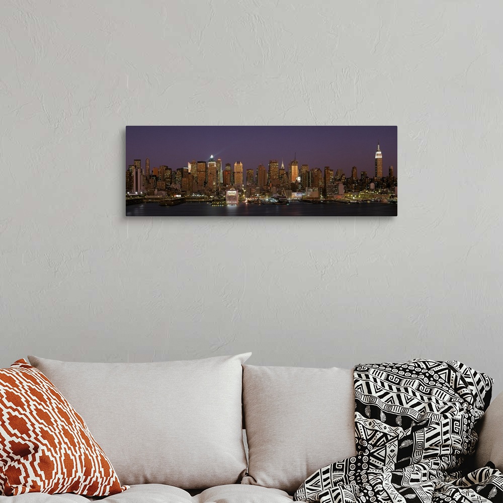 A bohemian room featuring Wide angel, distant photograph of the Manhattan skyline, lit at night, beneath a deep purple sky ...