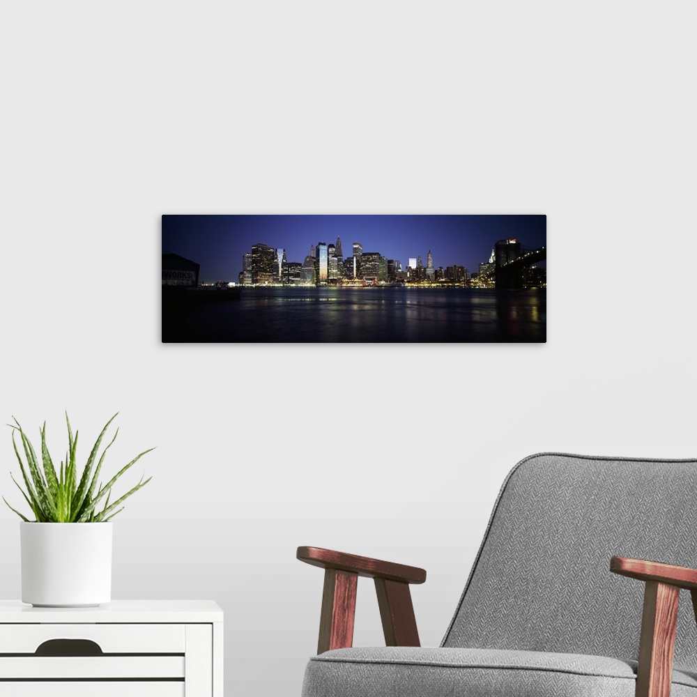 A modern room featuring Panoramic photo of the NYC cityscape lit up at night seen from the water.