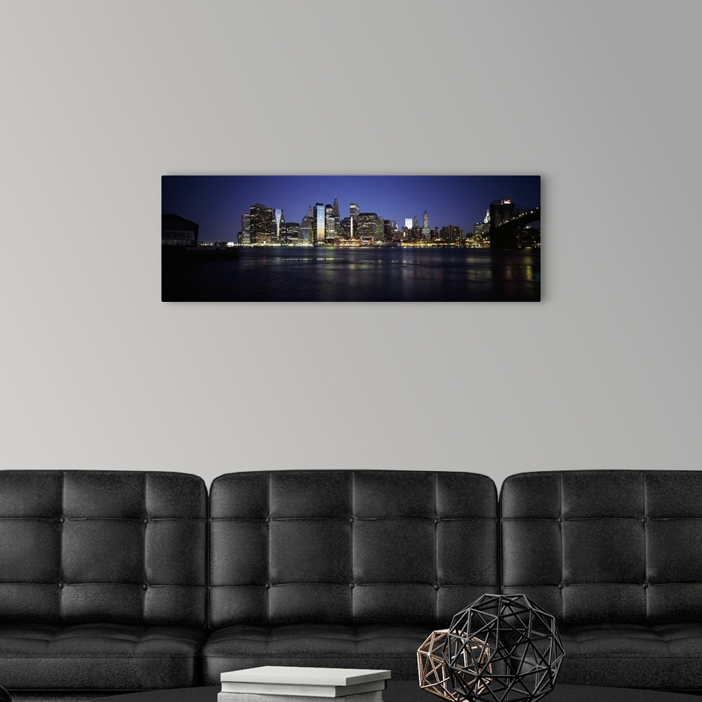 A modern room featuring Panoramic photo of the NYC cityscape lit up at night seen from the water.