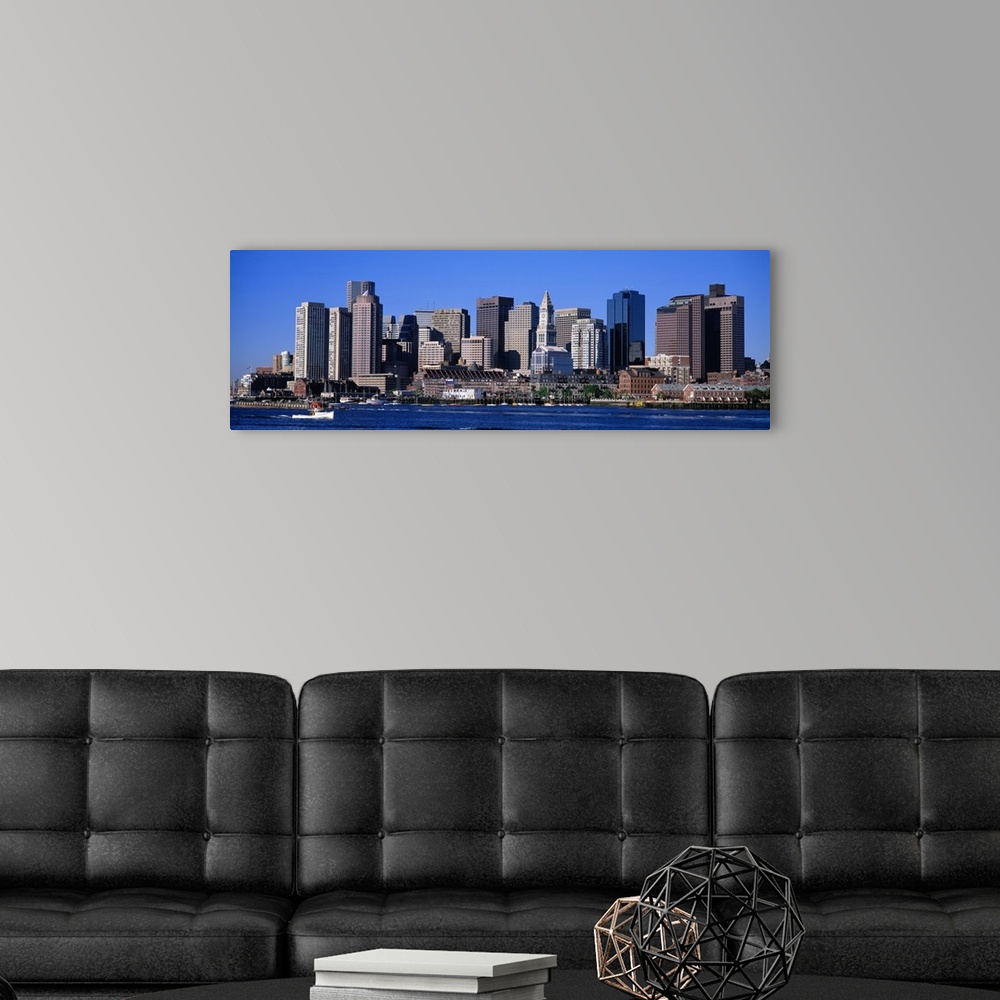 A modern room featuring A boat sailing across the water in front of the Boston skyline in Massachusetts.