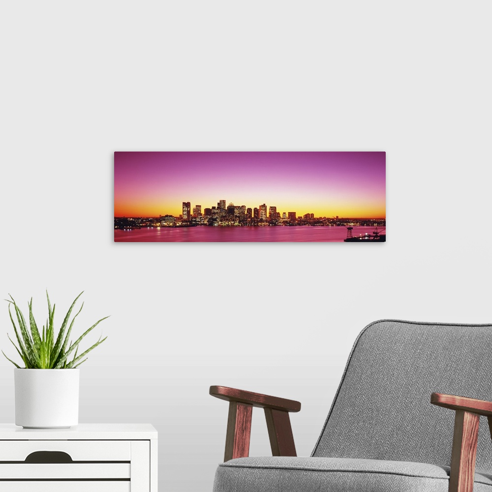 A modern room featuring Big, wide angle photograph of a distant Boston skyline, with lit skyscrapers at sunset.