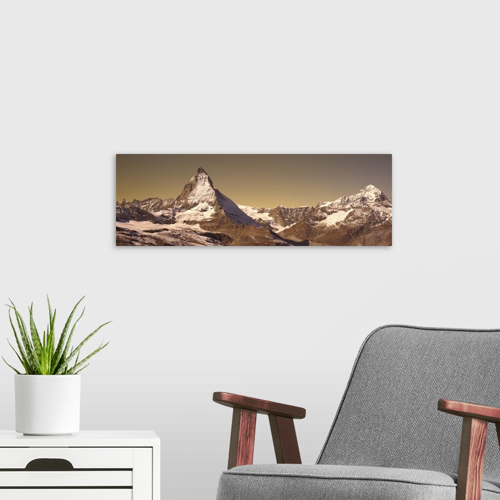 A modern room featuring Large, landscape photograph of Matterhorn mountain, lightly covered with snow, in Switzerland.