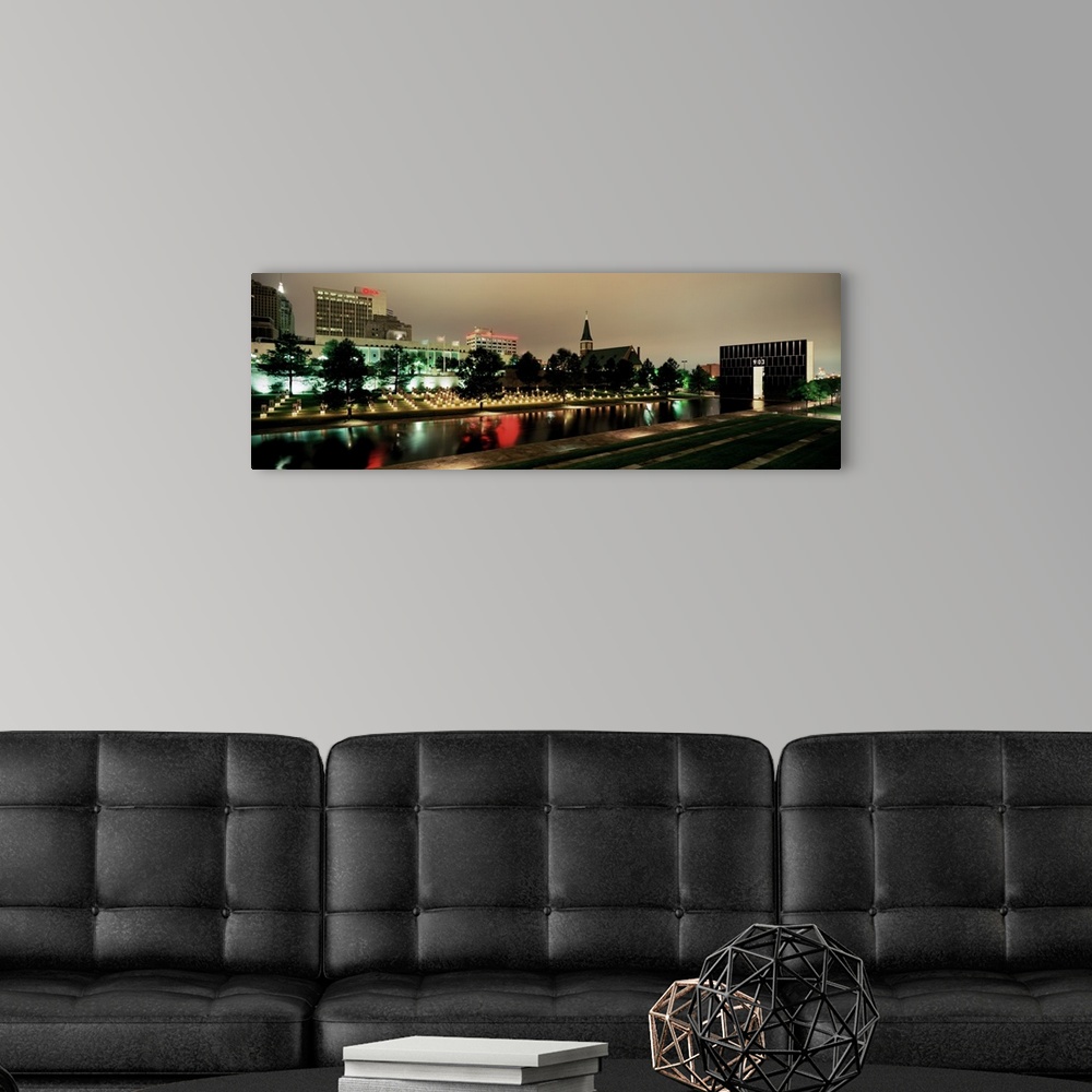 A modern room featuring Panoramic photograph of skyline and waterfront at nigh.  The building lights are reflected in the...