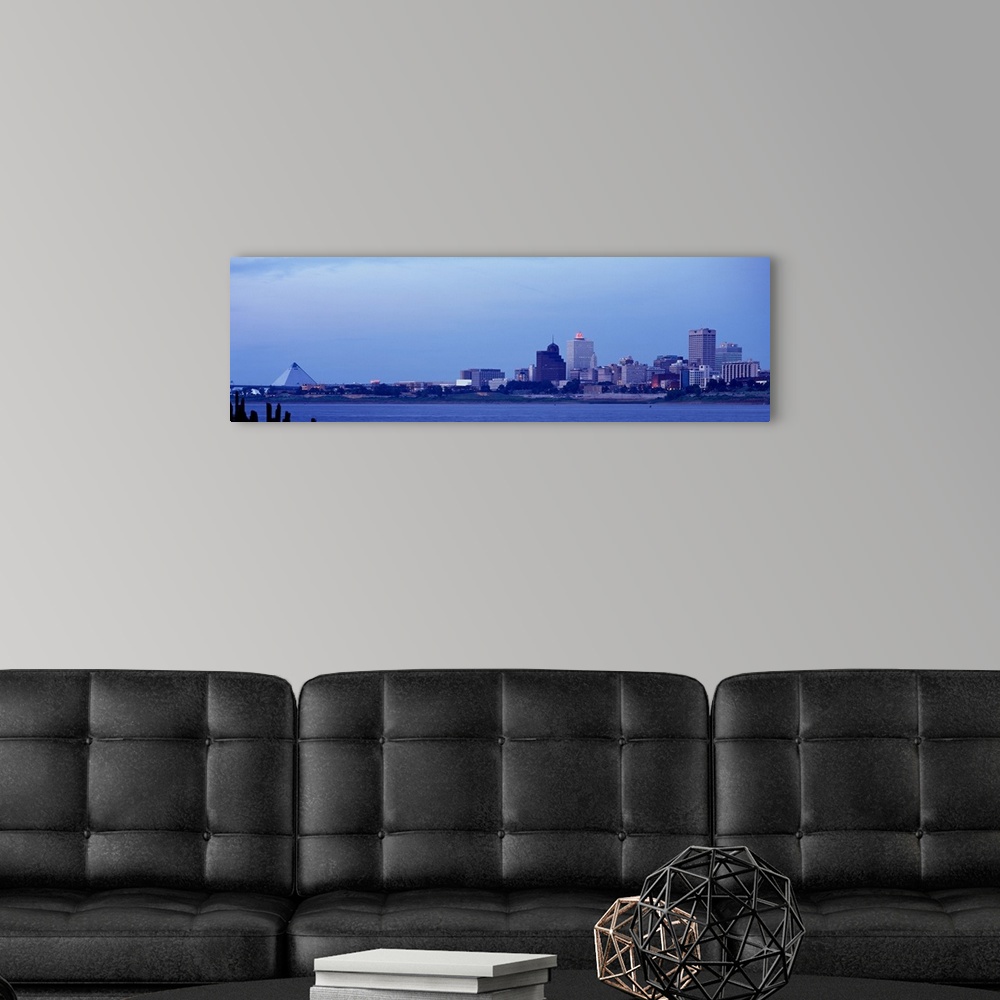 A modern room featuring The skyline in Memphis Tennessee is photographed from a distance across a body of water. There is...
