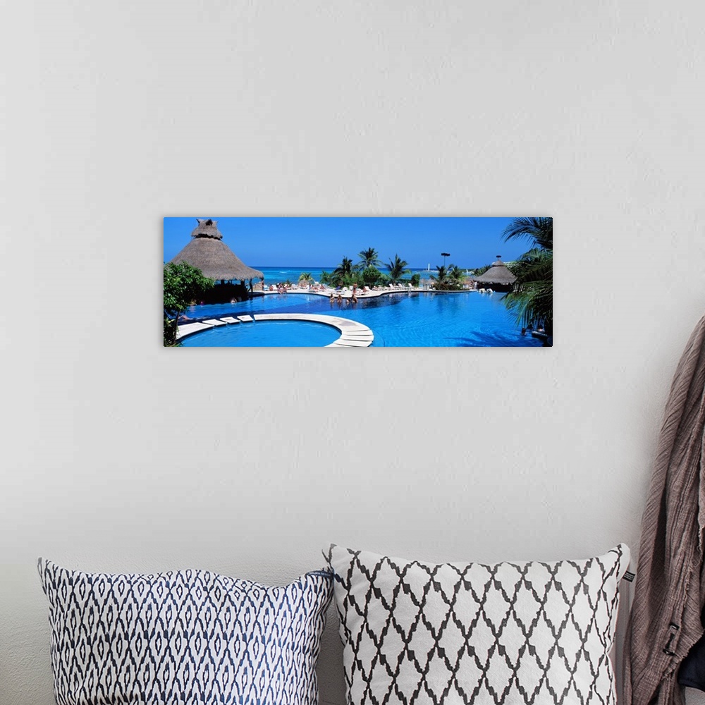 A bohemian room featuring Panoramic photo print of a big pool with people swimming in it with the ocean in the background.