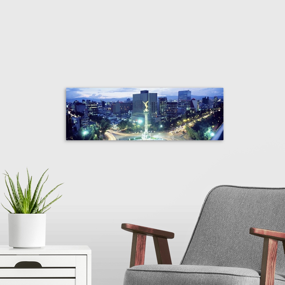 A modern room featuring Busy roundabout in a city in the evening with light trails from traffic circling the memorial pil...
