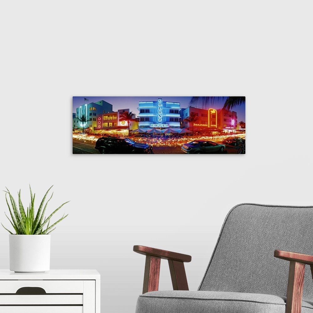 A modern room featuring Wide angle, giant photograph of a strip of brightly lit hotels and dance clubs at night, in Miami...