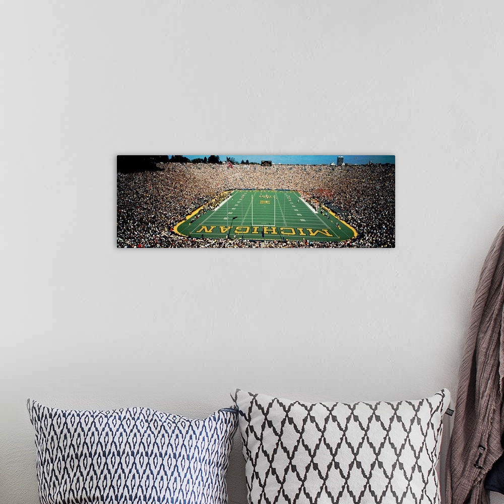 A bohemian room featuring Panoramic photograph of a college football stadium from behind a the goal.