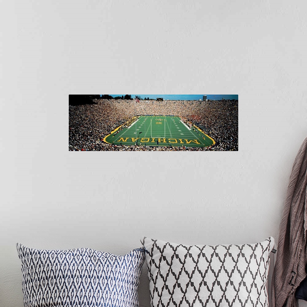 A bohemian room featuring Panoramic photograph of a college football stadium from behind a the goal.