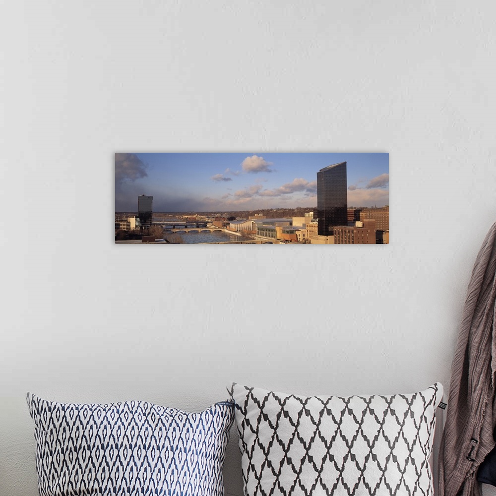 A bohemian room featuring The city skyline in Grand Rapids is photographed in panoramic view with a river cutting in betwee...