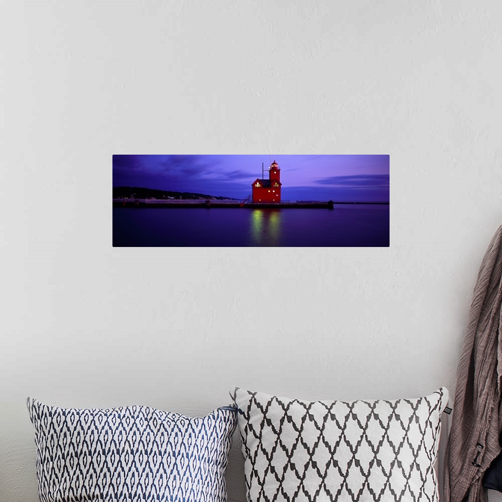 A bohemian room featuring A brightly colored lighthouse reflecting light onto the water at night in Holland, Michigan.