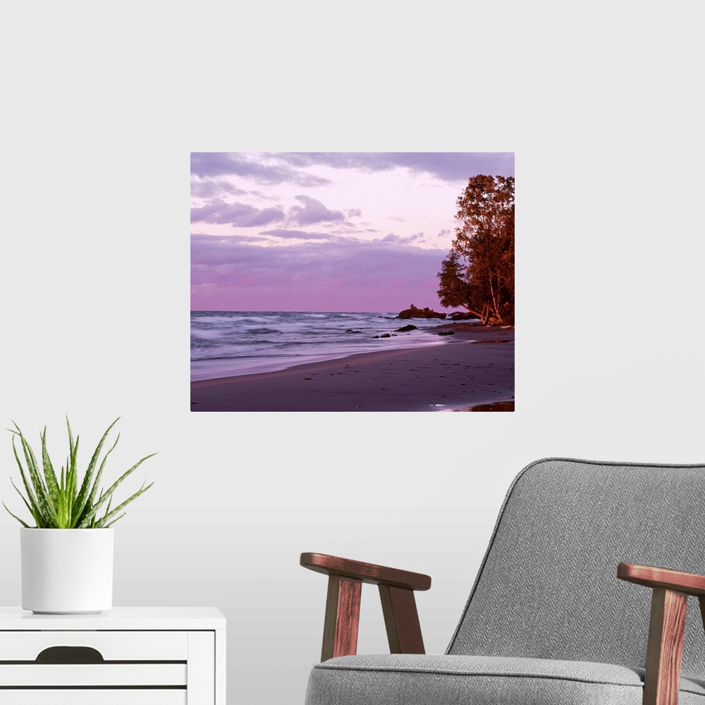 A modern room featuring Picture of waves in Lake Superior crashing on to the beach as the sun sets and lights up the sky ...