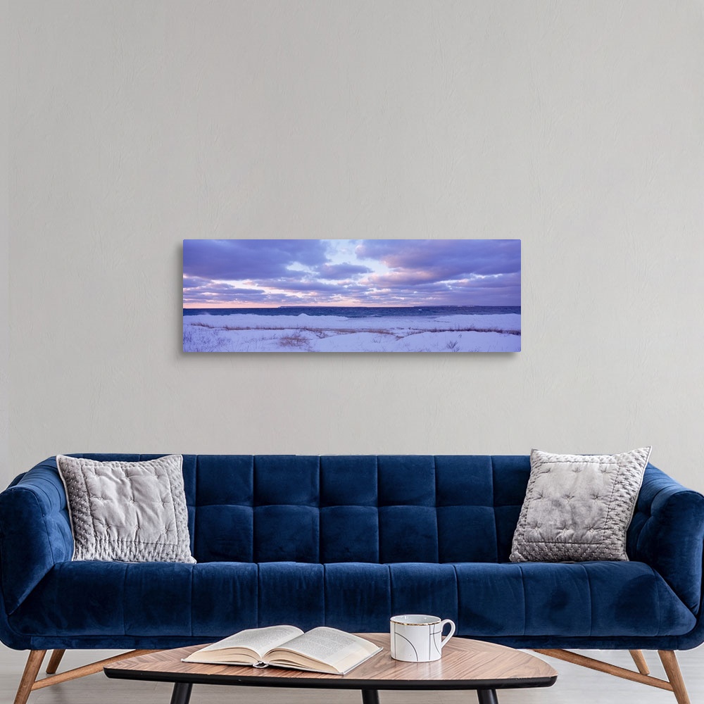 A modern room featuring Large, wide angle photograph of a beach off of Lake Michigan, under a sky of pastels and clouds a...