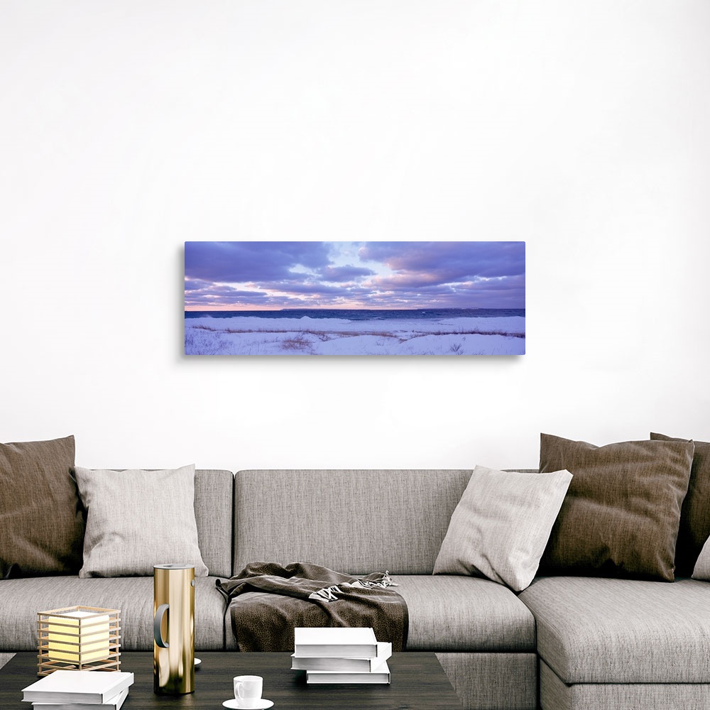 A traditional room featuring Large, wide angle photograph of a beach off of Lake Michigan, under a sky of pastels and clouds a...