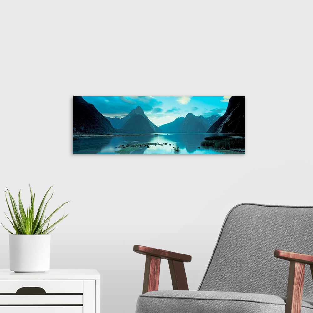 A modern room featuring Mountains reflecting in the smooth surface of a lake in this landscape panoramic photograph.