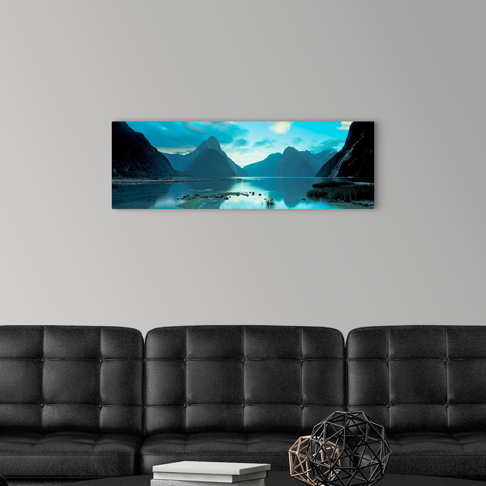 A modern room featuring Mountains reflecting in the smooth surface of a lake in this landscape panoramic photograph.