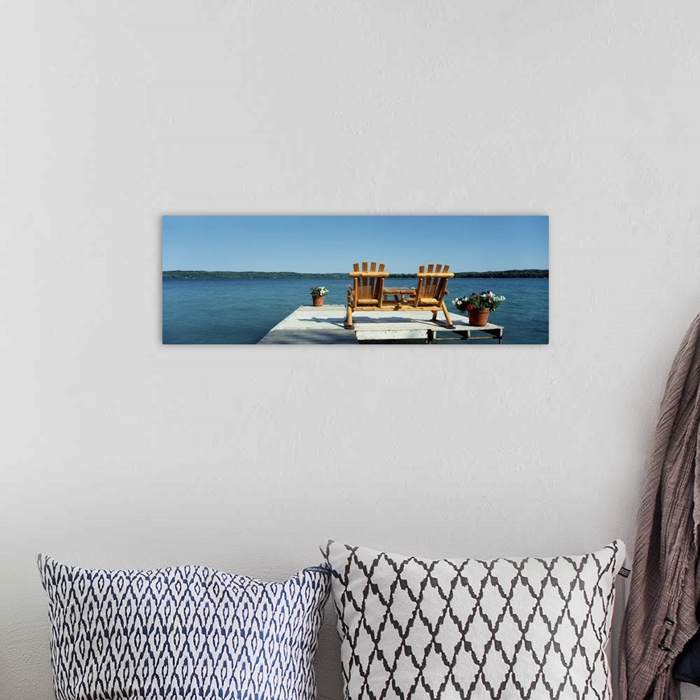 A bohemian room featuring This panoramic photograph is taken from behind two chairs sitting on a dock looking out over a bo...