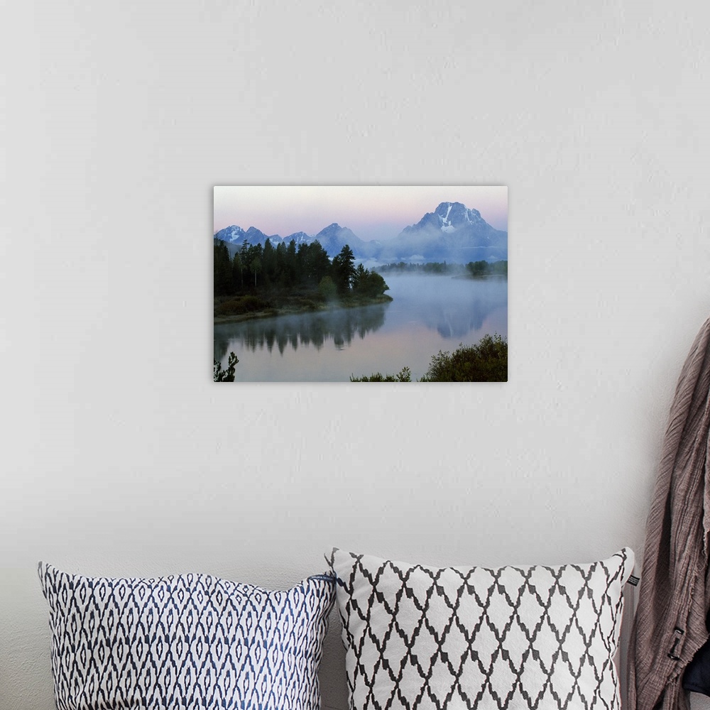 A bohemian room featuring A large photograph showing forest and foilage surrounding water with mountains in the background ...