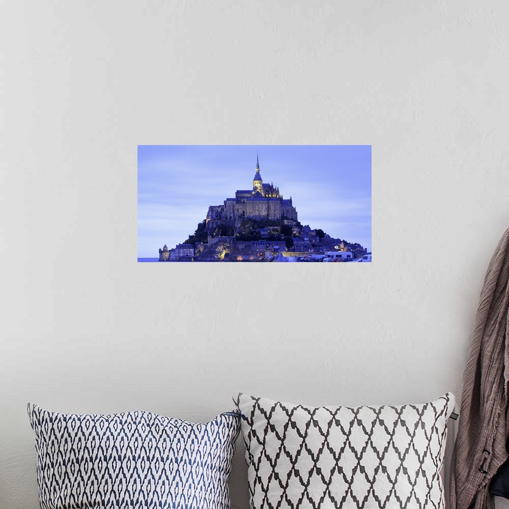 A bohemian room featuring Dusk shot of a lit up castle sitting high on a small rocky island in the water.