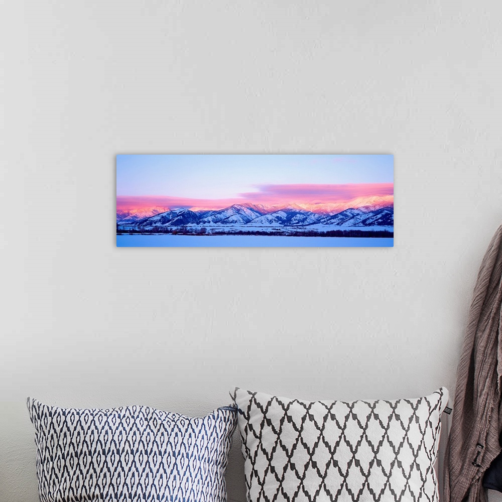 A bohemian room featuring A panoramic snowscape photograph of plains and clouds passing over mountains at the end of the day.