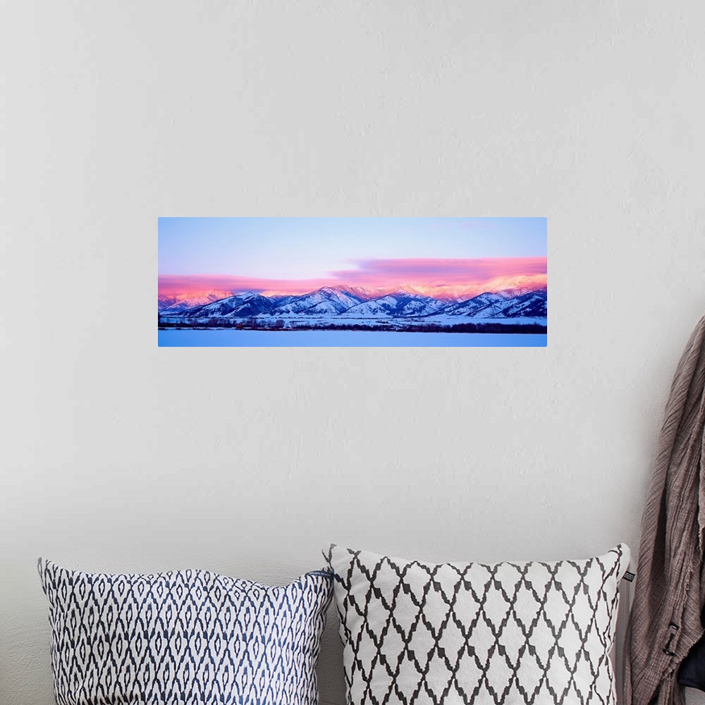A bohemian room featuring A panoramic snowscape photograph of plains and clouds passing over mountains at the end of the day.