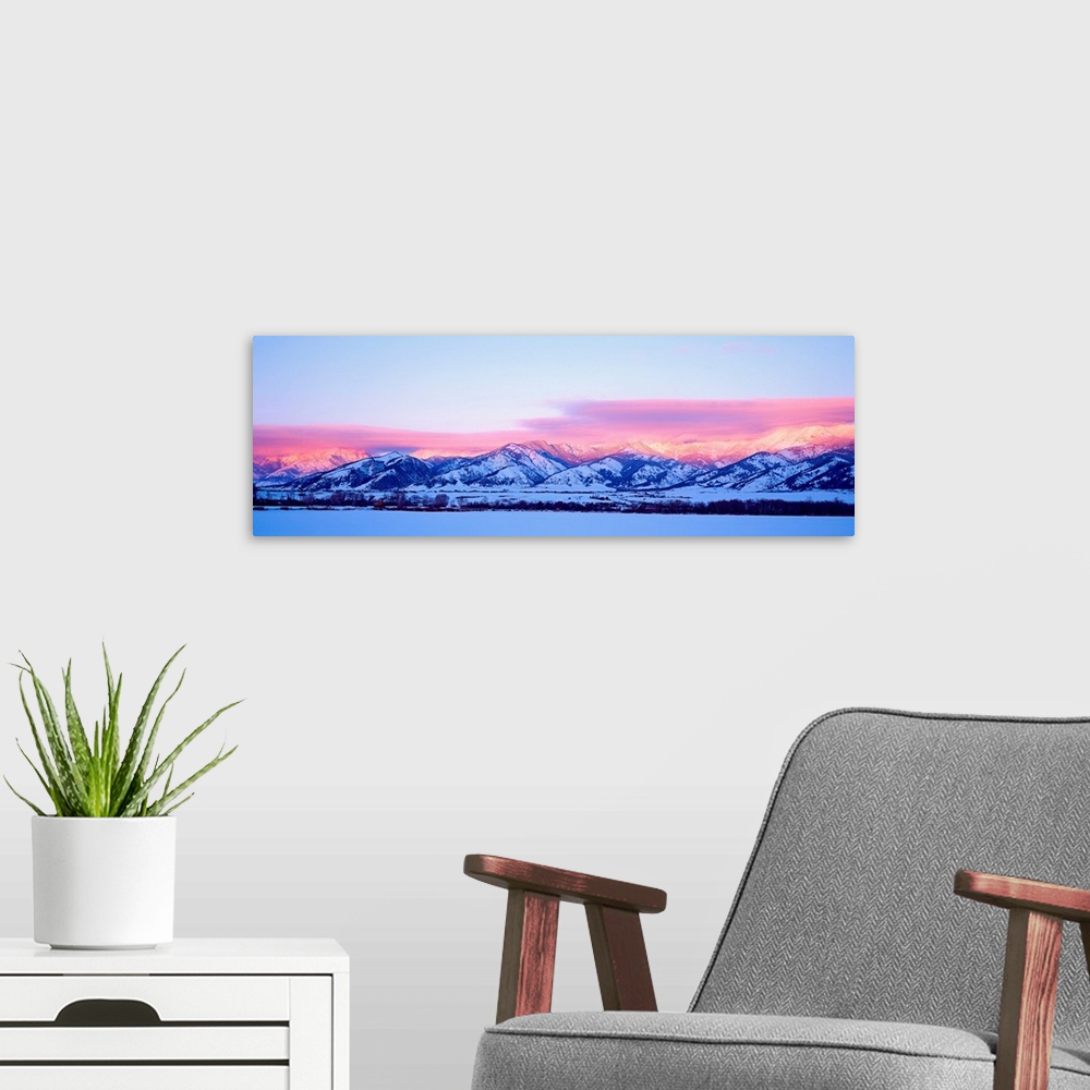 A modern room featuring A panoramic snowscape photograph of plains and clouds passing over mountains at the end of the day.