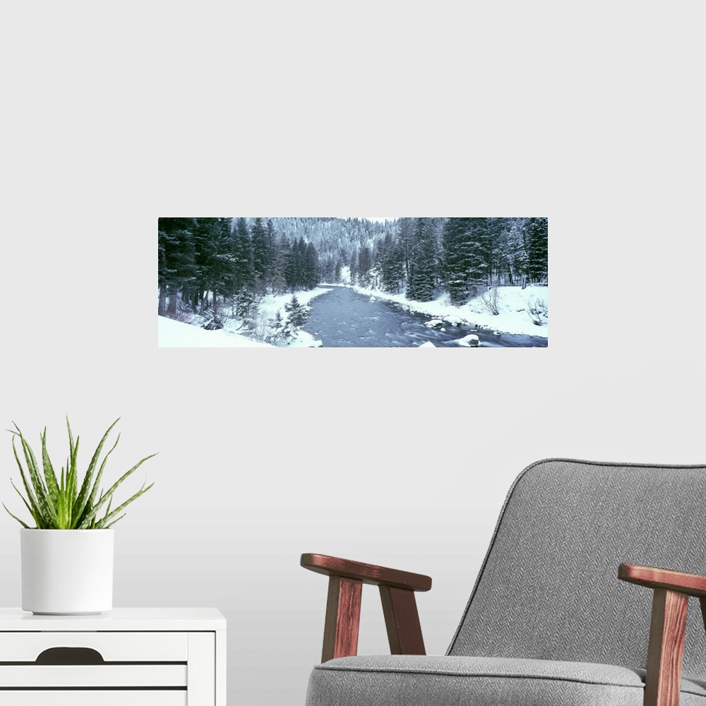 A modern room featuring This large panoramic shot was taken of a river during winter with the land covered in snow beside...