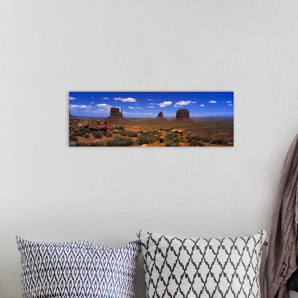 A bohemian room featuring Panoramic photo on canvas of three tall rock formations in the desert under a bright blue sky.